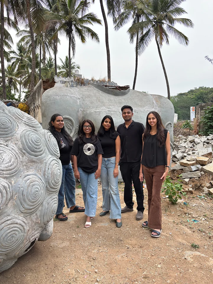 The team beside a large stone sculpture