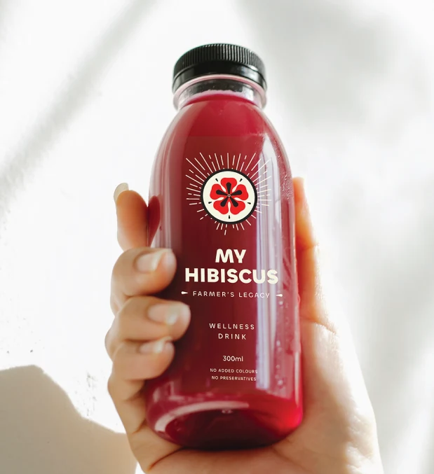 A hand holding a bottle of My Hibiscus wellness drink